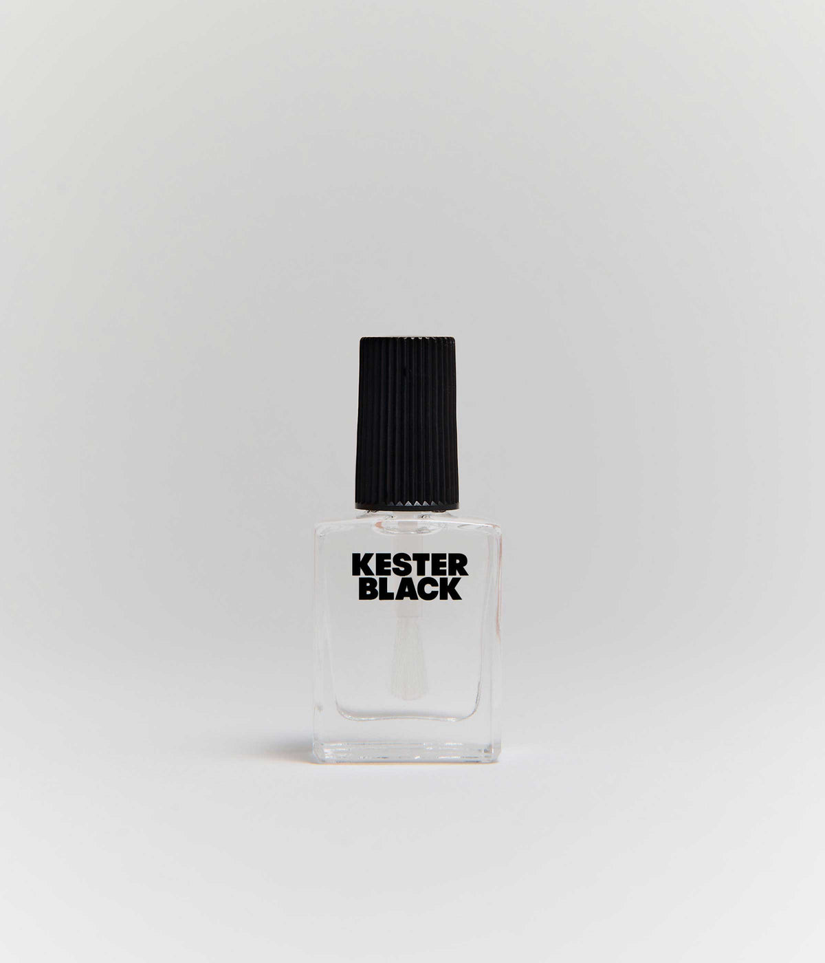 A clear nail polish bottle with a black cap centered against a light grey studio background.